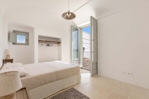 A bedroom with a bed, bedside table, lamp, and a view of the outside balcony. - Masseria Stella del Monte by Perle di Puglia (Cisternino)