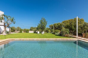 A clear blue swimming pool with a stone border, surrounded by a well-maintained lawn and trees. - Masseria Stella del Monte by Perle di Puglia (Cisternino)