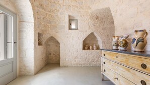 Cocina con paredes de piedra, un aparador de madera y macetas de cerámica.