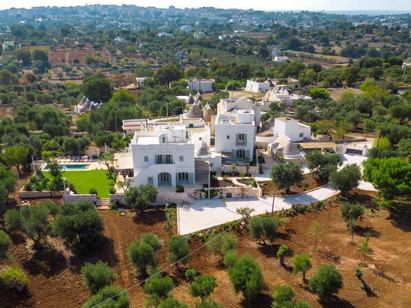 A residential area with white buildings, a swimming pool, and olive trees. - Masseria Stella del Monte by Perle di Puglia (Cisternino)