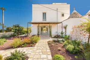 A white building with a stone pathway leading to a covered entrance. - Masseria Stella del Monte by Perle di Puglia (Cisternino)