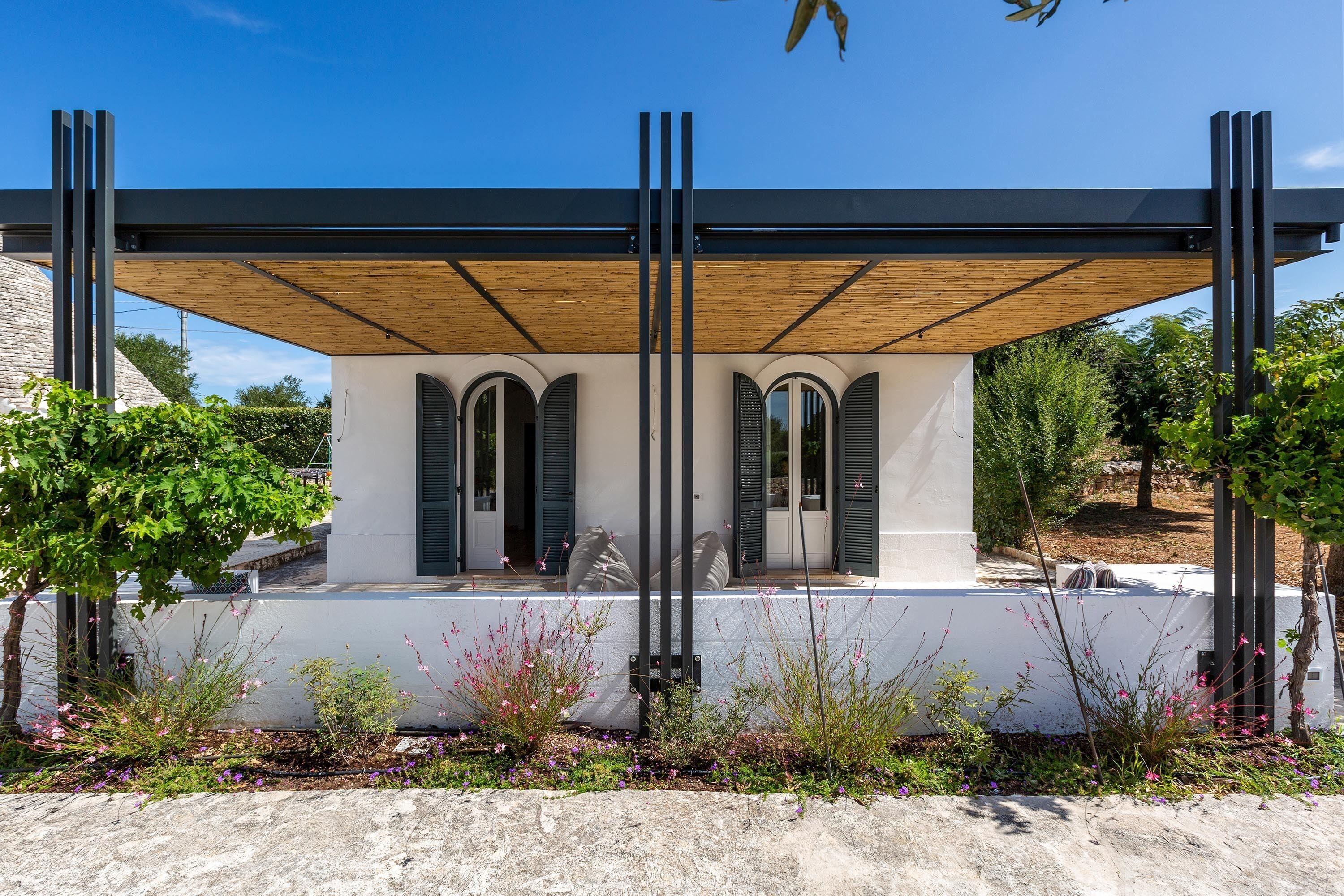 Un bâtiment moderne doté d’un patio couvert, de fenêtres en arc de cercle et d’une façade blanche.