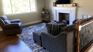 A living room with a fireplace, a television, and a large window.
