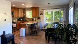 A spacious kitchen with wooden cabinets, a central island, and a dining area with a view of the outdoors.