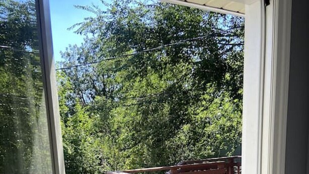A wooden deck with a railing, a bench, and a door leading to an outdoor area.