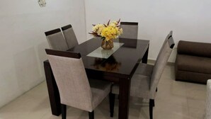 A dining area with a rectangular table, four chairs, and a vase of yellow flowers. - Apartamento en Pitalito (Pitalito)