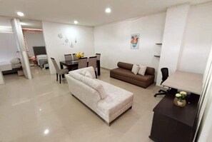 A modern living room with a sofa, a dining table with chairs, and a small desk with a lamp. - Apartamento en Pitalito (Pitalito)