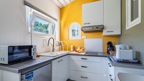 Pieni, käytännöllinen keittiö, jossa on valkoiset kaapit, mikroaaltouuni, pesuallas ja kahvinkeitin.
