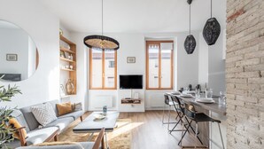 A modern living room with a sofa, coffee table, and a dining area with a kitchen counter.