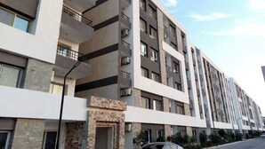 A multi-story residential building with balconies, a parking area, and a clear sky. - Chalet for rent in fanadir bay resort  (Hurghada)