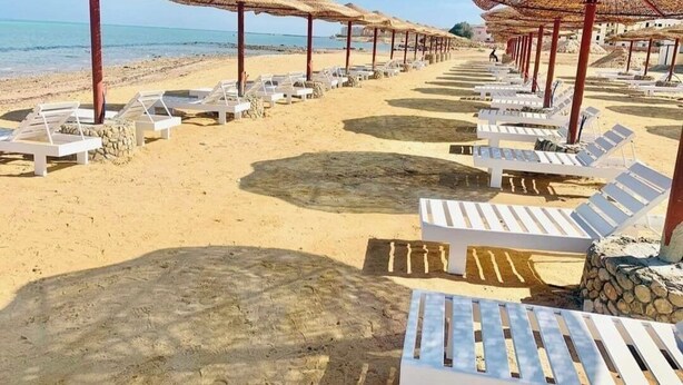 A beach with rows of white lounge chairs and thatched umbrellas. - Chalet for rent in fanadir bay resort  (Hurghada)