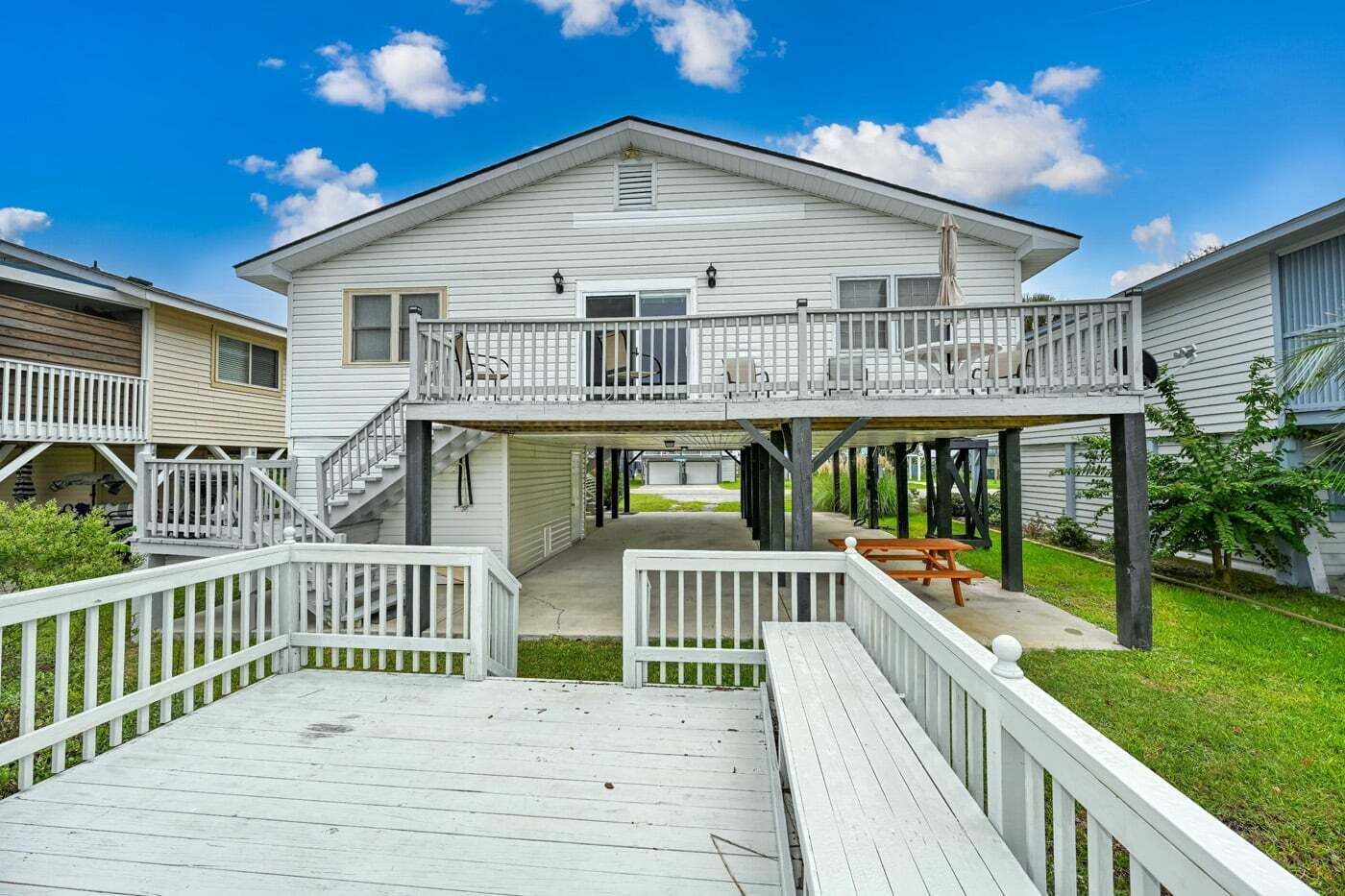 Een tweelaags huis met een balkon, een terras en een overdekt buitengebied.