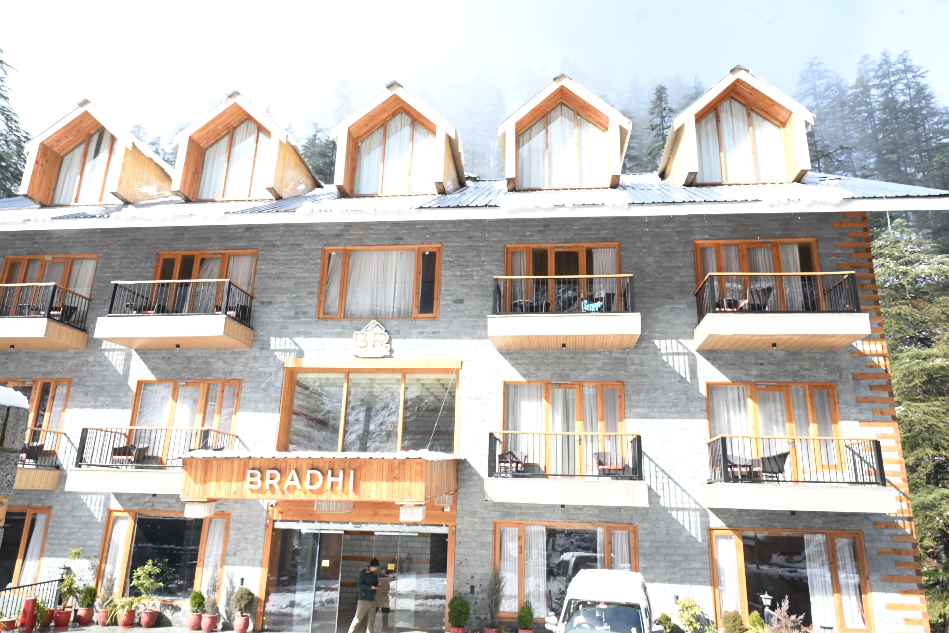 A multi-story hotel with a prominent 'BRADHI' sign, balconies on each floor, and a stone facade.