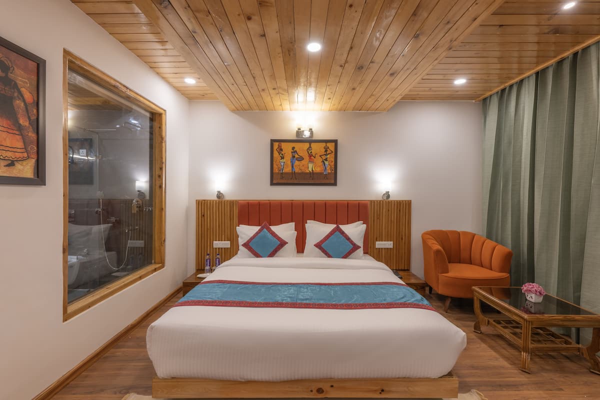 A hotel room with a large bed, a wooden ceiling, a painting on the wall, and a view of the outside.