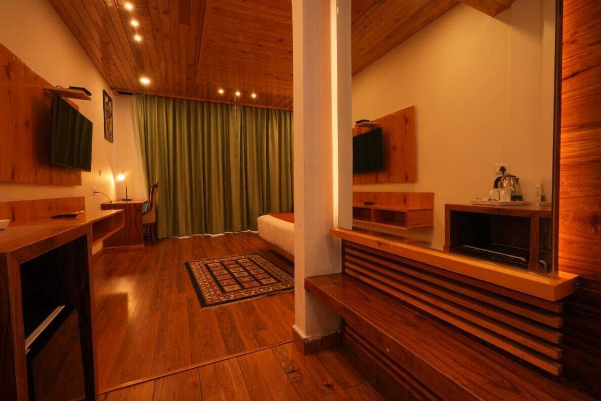 A wooden-floored room with a television, a fireplace, and a green curtain.