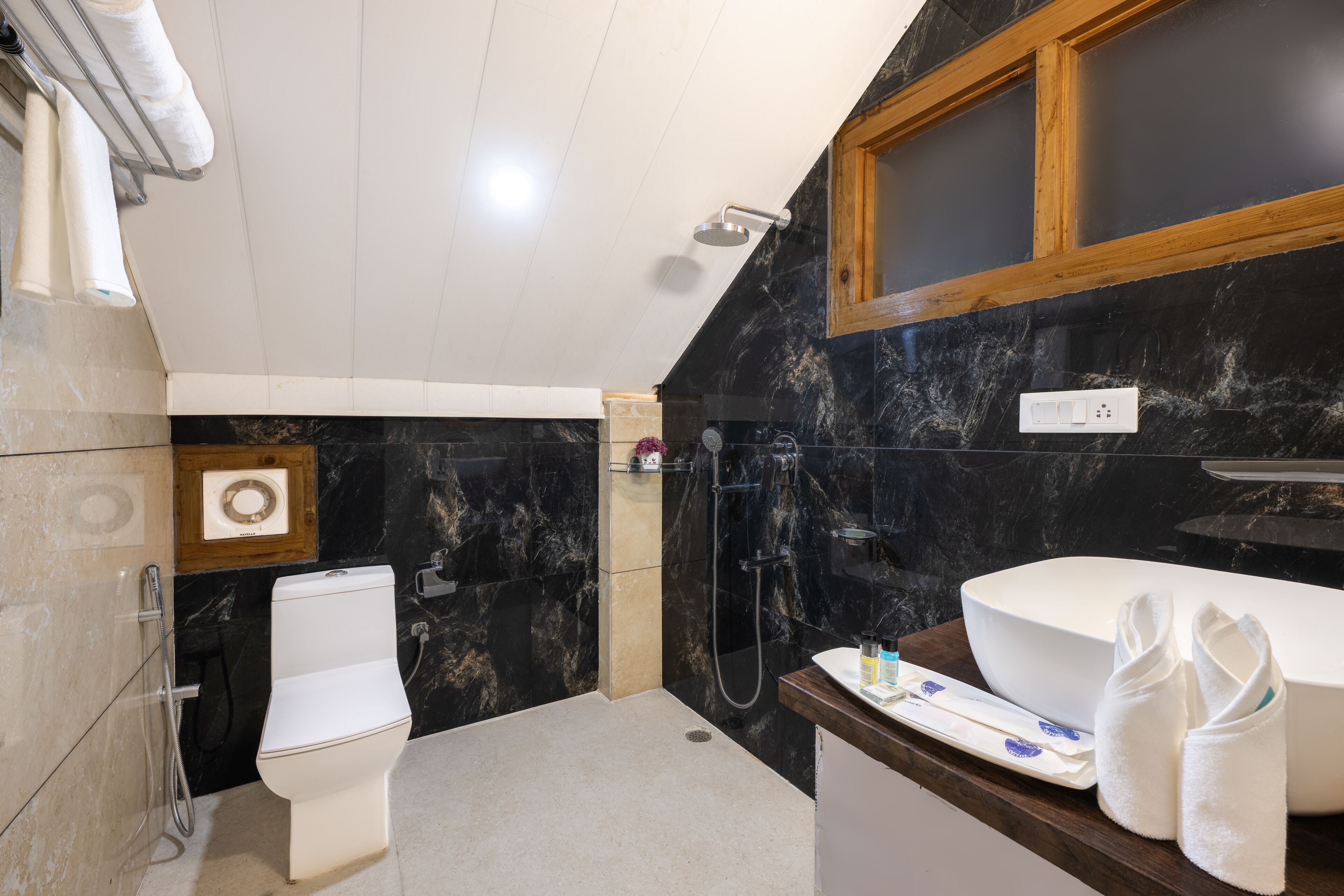 A modern bathroom with a white toilet, a large white sink, and a shower area.