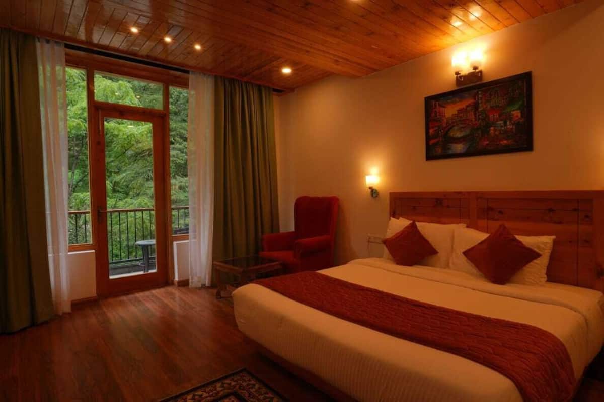 A bedroom with a large bed, a red chair, a painting on the wall, and a balcony with curtains.