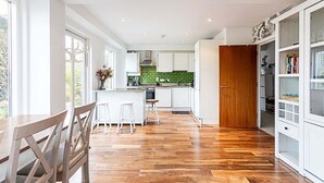 Eine moderne Küche mit weißen Schränken, einer grünen Spritzschutzwand und Holzboden.