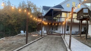 Ein Haus mit überdachter Veranda, Gartenmöbeln und Lichterketten.