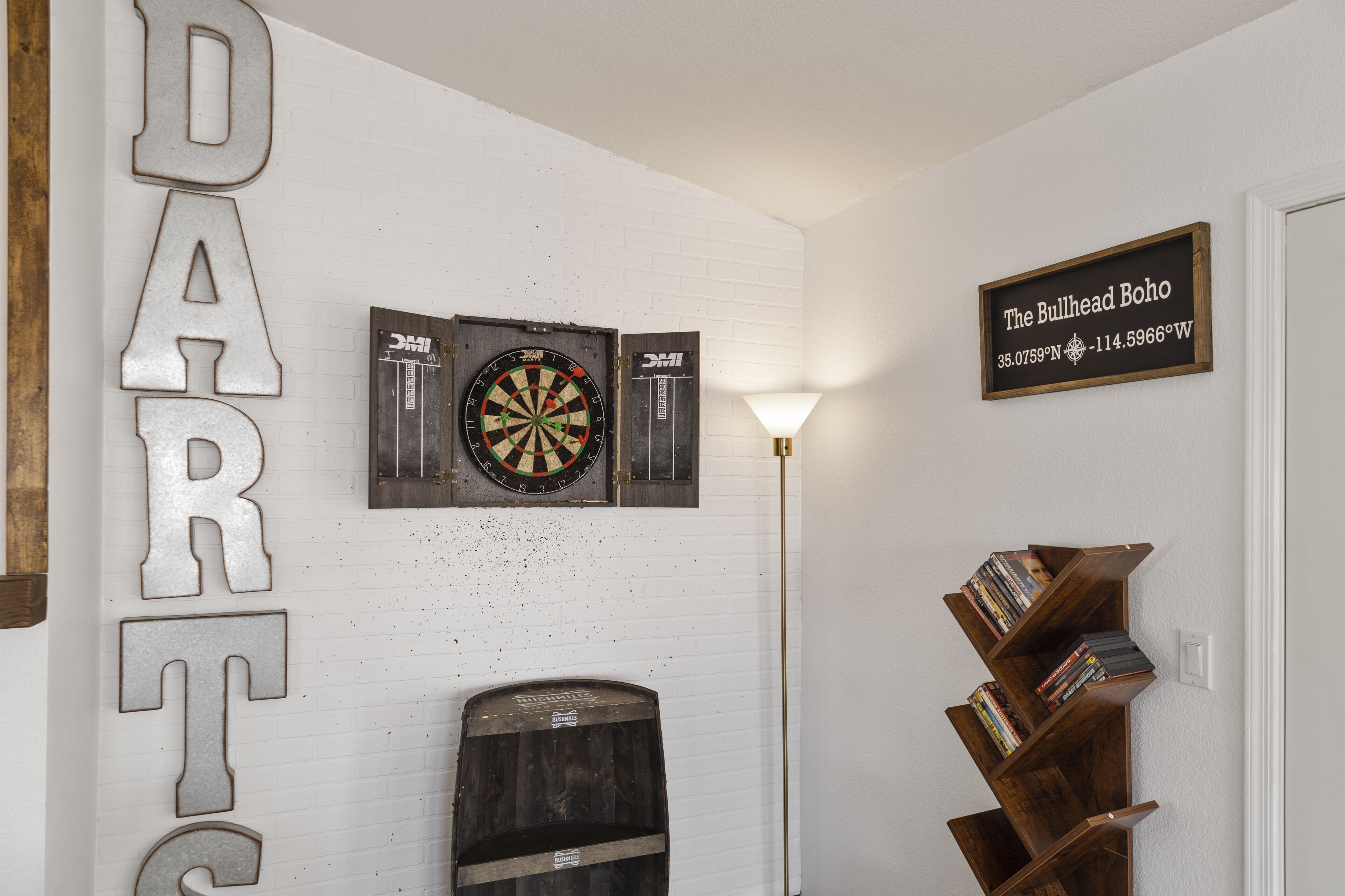 Ein Zimmer mit Dartscheibe, Bücherregal und einem Schild mit der Aufschrift 'The Bullhead Boho'.
