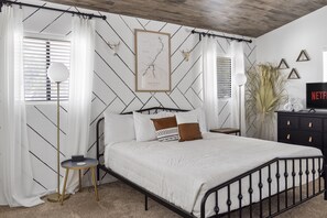 A bedroom with a bed, curtains, a map on the wall, a TV, and a plant. - PRIVATE Launch & Beach, 3 Bd, 2 Ba - "The Bullhead Boho" (Bullhead City)