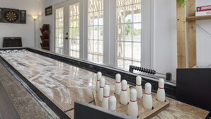 Een bowlingbaan met een houten baan, neergezet poolstok en ramen met decoratieve roosters.