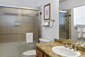 A bathroom with a glass shower door, a white toilet, a granite countertop sink, and a mirror. - PRIVATE Launch & Beach, 3 Bd, 2 Ba - "The Bullhead Boho" (Bullhead City)