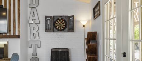 Ein Zimmer mit Dartscheibe, Bücherregal und einer Tür mit Glasverkleidung.
