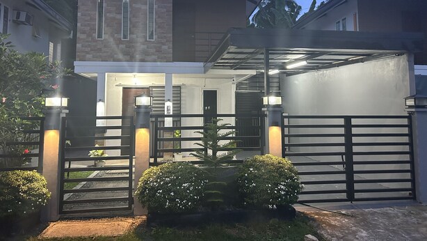 A modern two-story house with a covered entrance, a gated driveway, and well-maintained landscaping. - Private townhouse, located in a private subdivision with guards on site.  (San Pablo City)