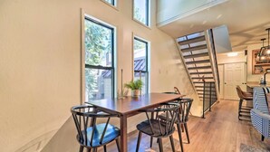 Un comedor con una mesa y sillas de madera, una escalera y vistas al exterior.