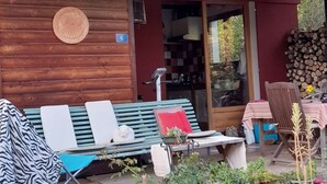 Una cabaña de madera con un porche cubierto, una banca y una mesa.