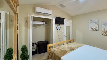 Une chambre à coucher avec un lit, une armoire, une télévision et une horloge au mur.