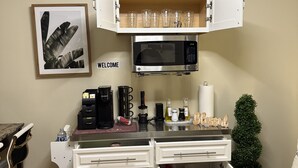 Eine kleine Küchenzeile mit Mikrowelle, Kaffeemaschine und verschiedenen Geräten.