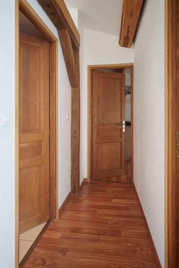 Un couloir avec des portes en bois et une poutre en bois au plafond.