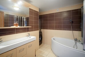 A modern bathroom with a white sink, a built-in washing machine, and a standalone bathtub with a showerhead. - Le Richebourg (Gevrey-Chambertin)