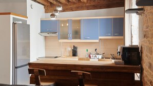 Una cocina con armarios de madera, un refrigerador, una cafetera y un comedor con una mesa y sillas de madera.