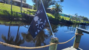 Een vlag met een schedel en kruisbessen symbool, vastgebonden aan een houten paal met touw.