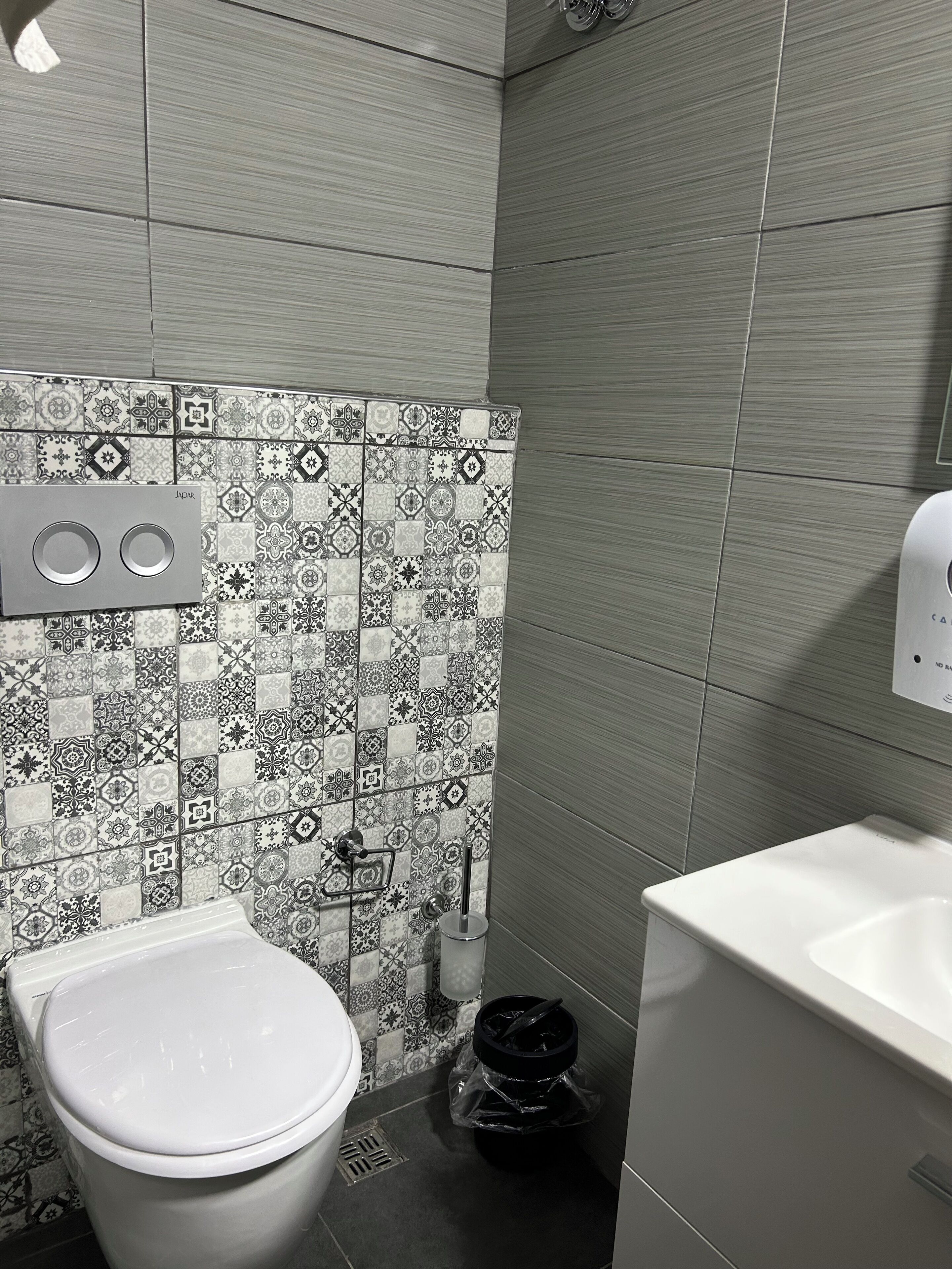 Une salle de bain avec des toilettes, un lavabo et des carreaux décorés.