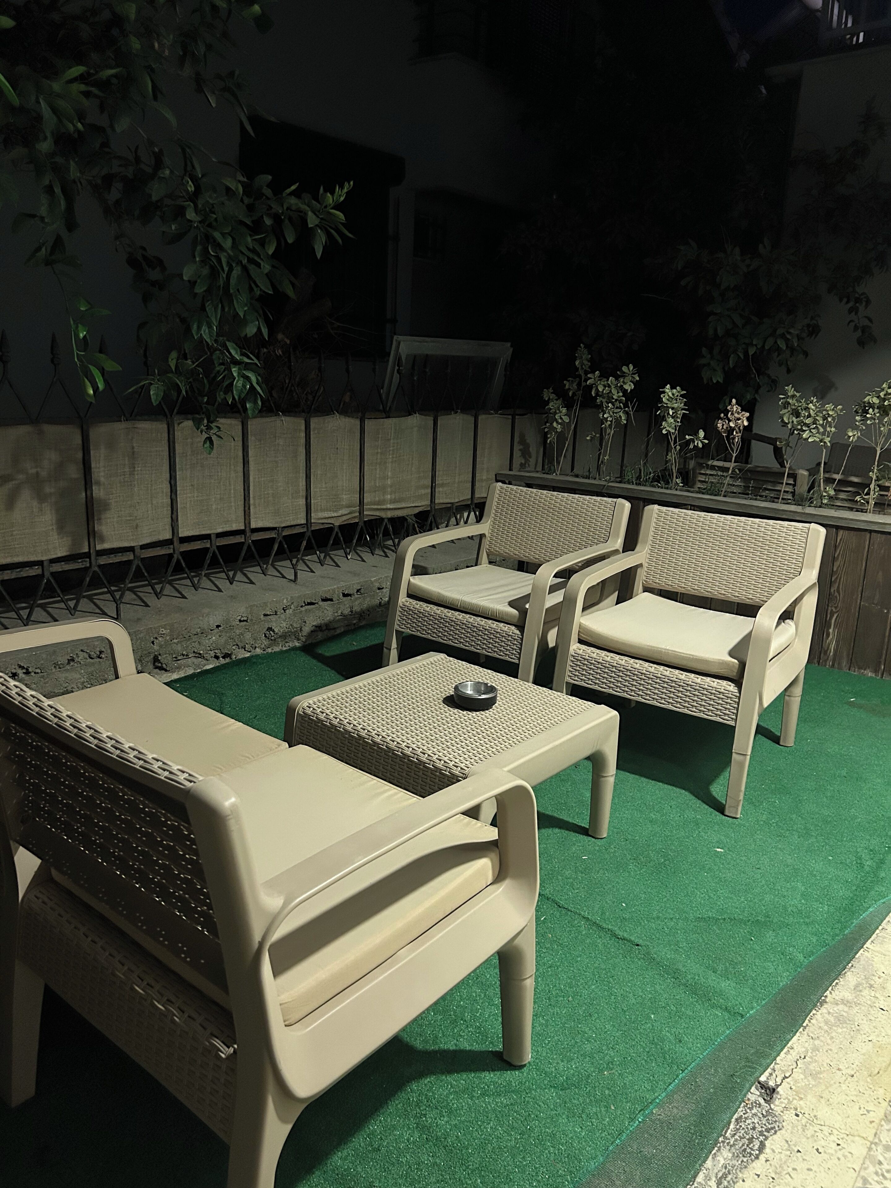 Un área de estar al aire libre con mobiliario de mimbre y piso de césped artificial verde.