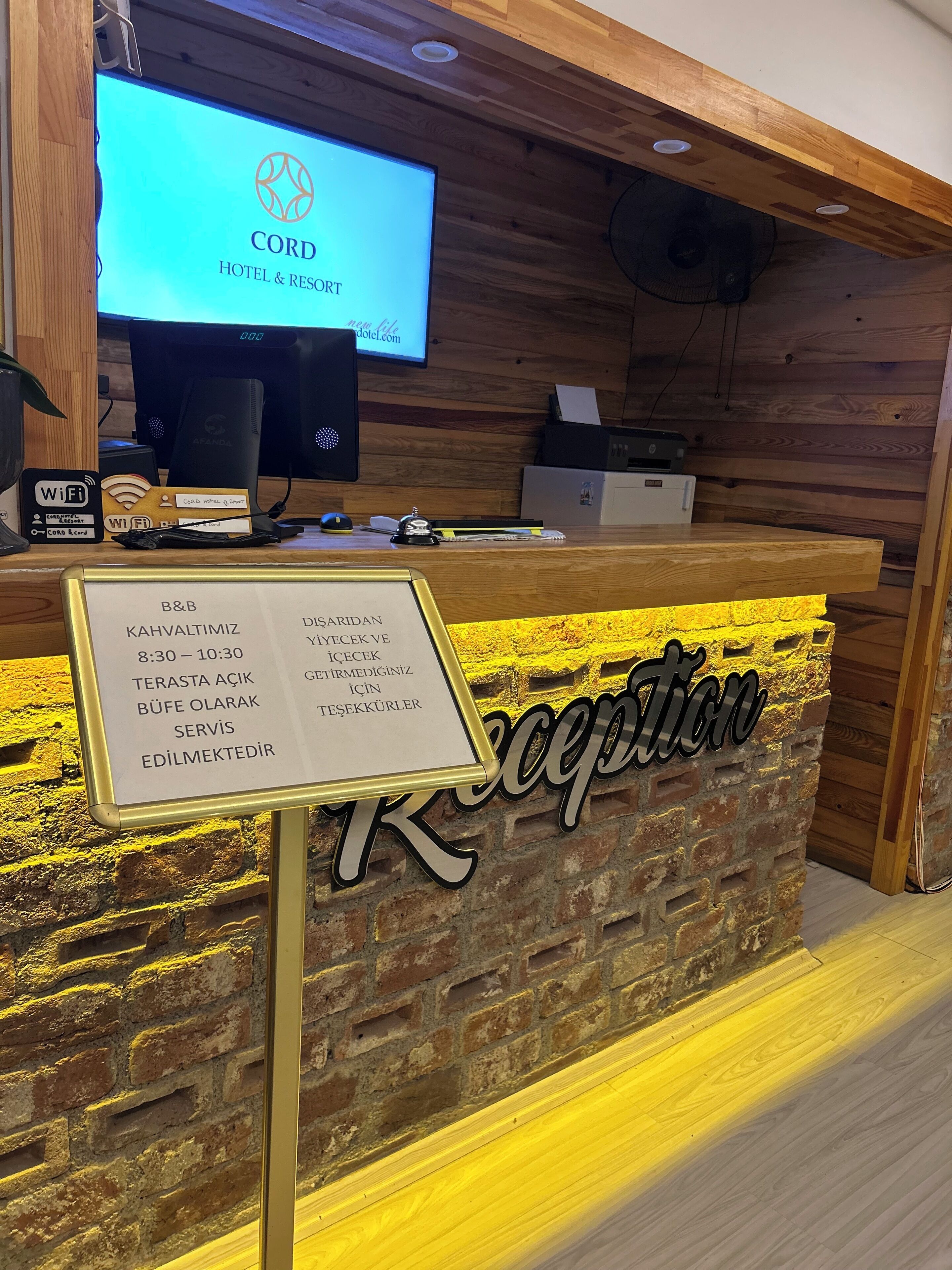 A reception desk with a wooden backdrop and a sign indicating the reception hours.