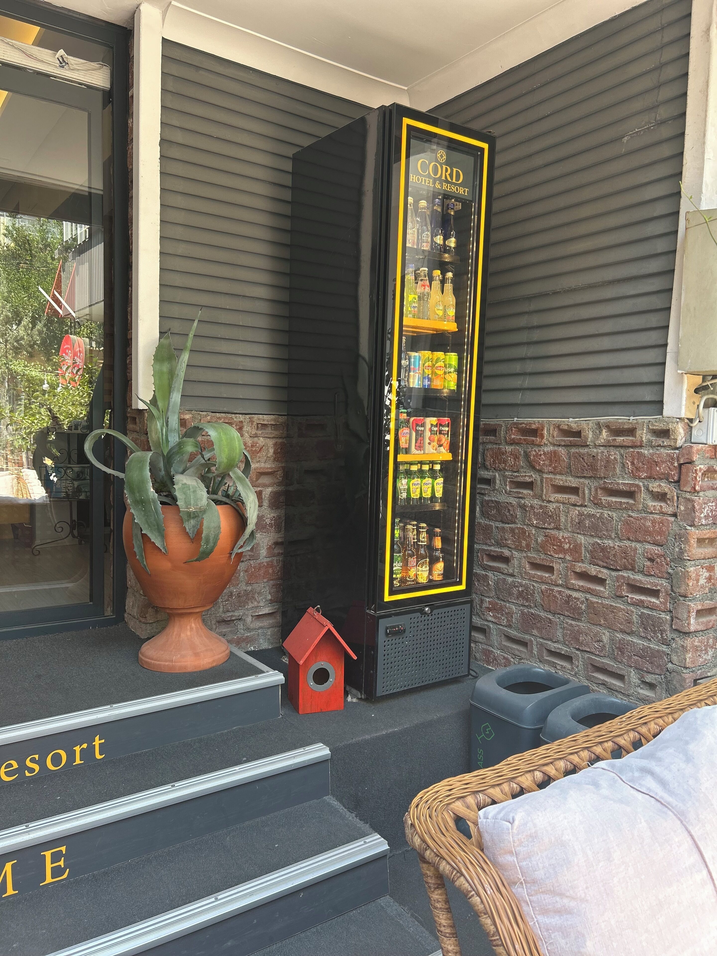 Een etalage met een automaat met de tekst 'CORD HOTEL & RESORT' en een klein vogelhuisje.