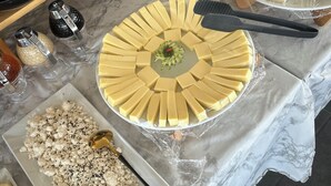 Una mesa de buffet con diversos alimentos, como queso, frutos secos y frutas, sobre un mantel de mármol.