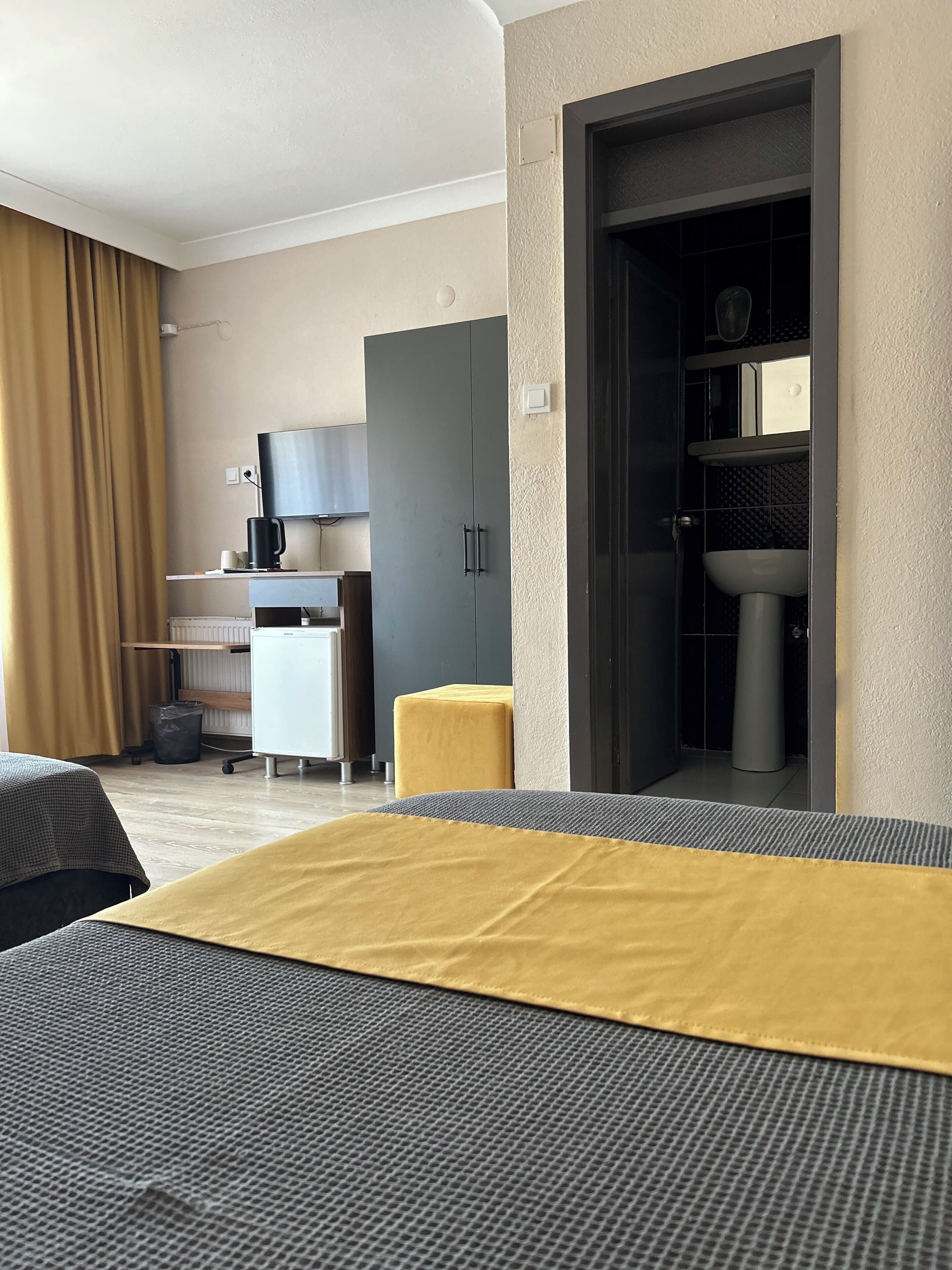 A hotel room with a bed, a desk, a chair, a television, and a bathroom.