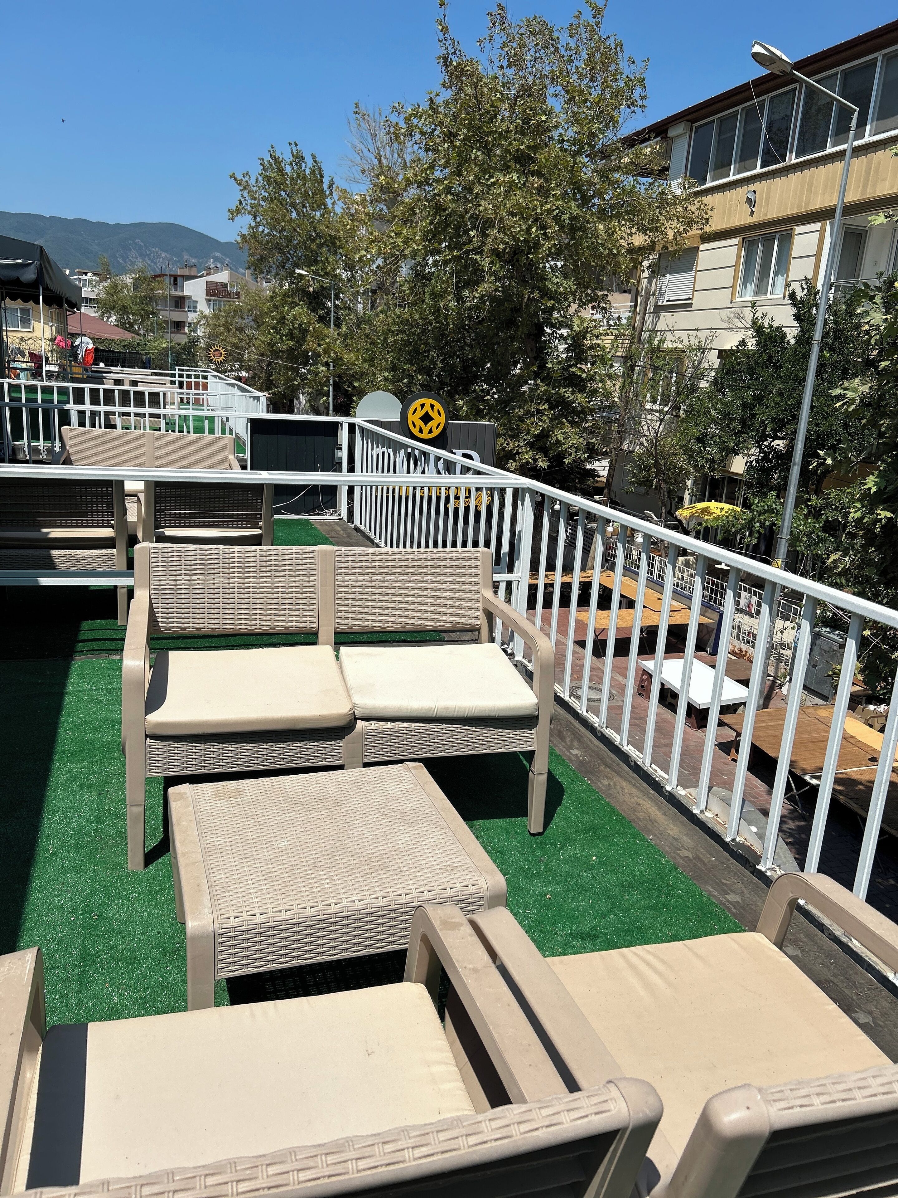 A rooftop terrace with wicker lounge chairs and a white railing.