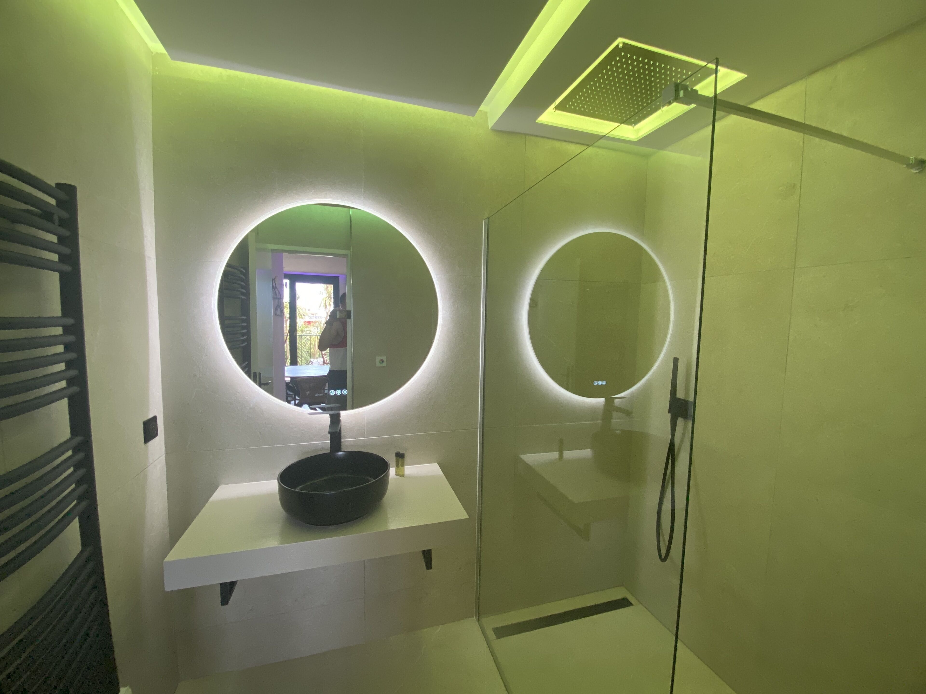 A modern bathroom with a round mirror, a sink, and a shower.