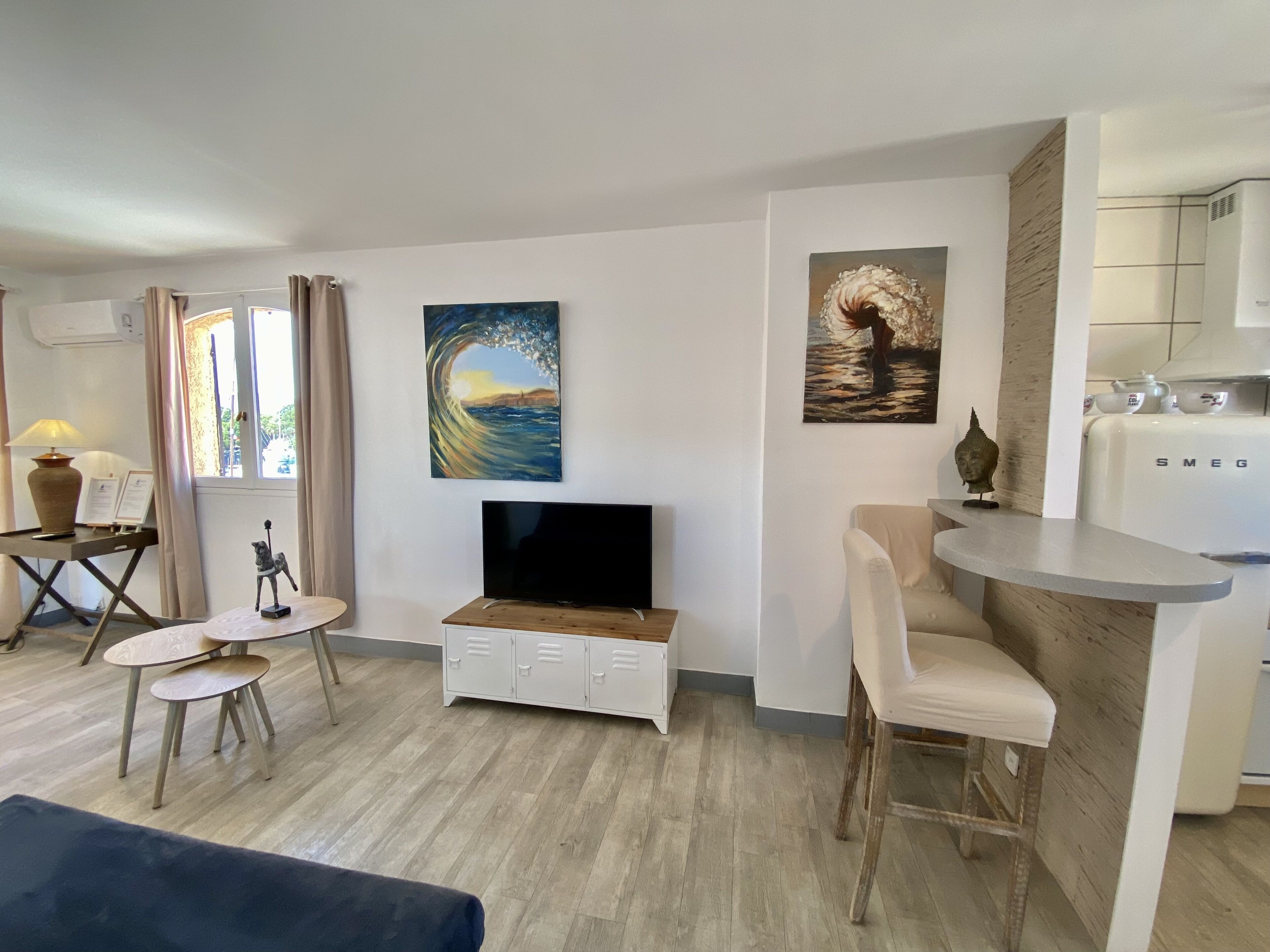 A modern living room with a TV, a small dining area, and a kitchen area.