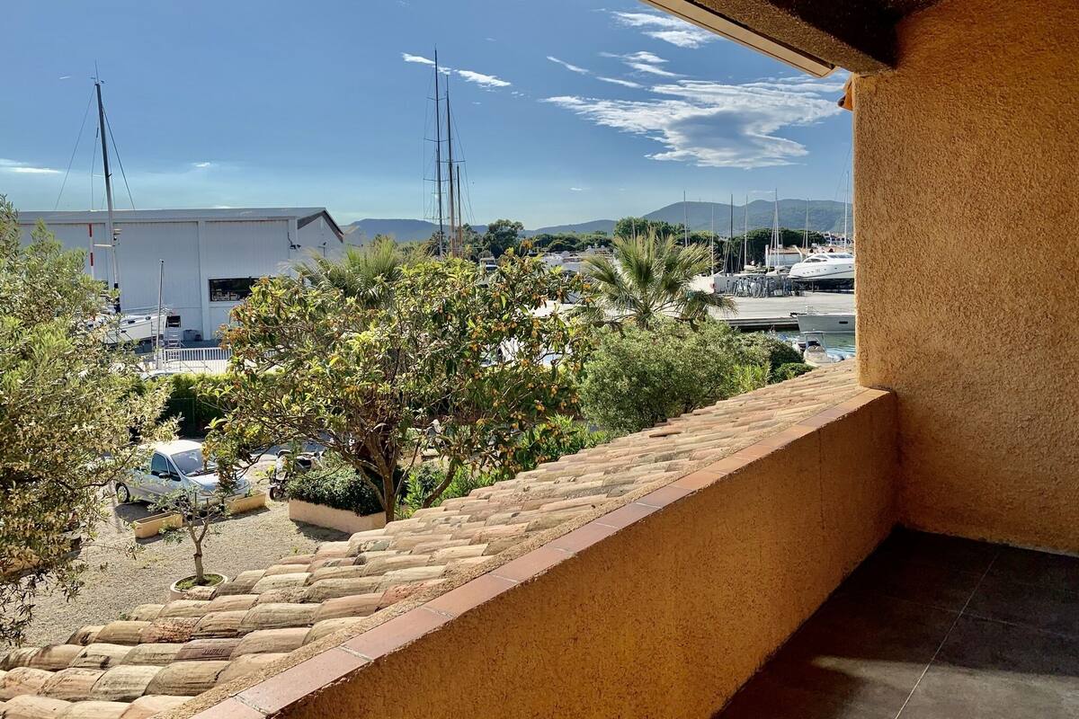 A balcony with a view of a marina, boats, and distant mountains.