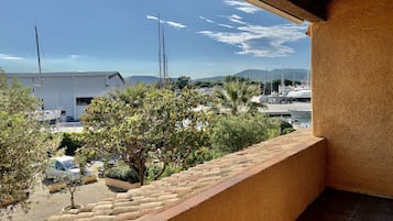 A balcony with a view of a marina, boats, and distant mountains.