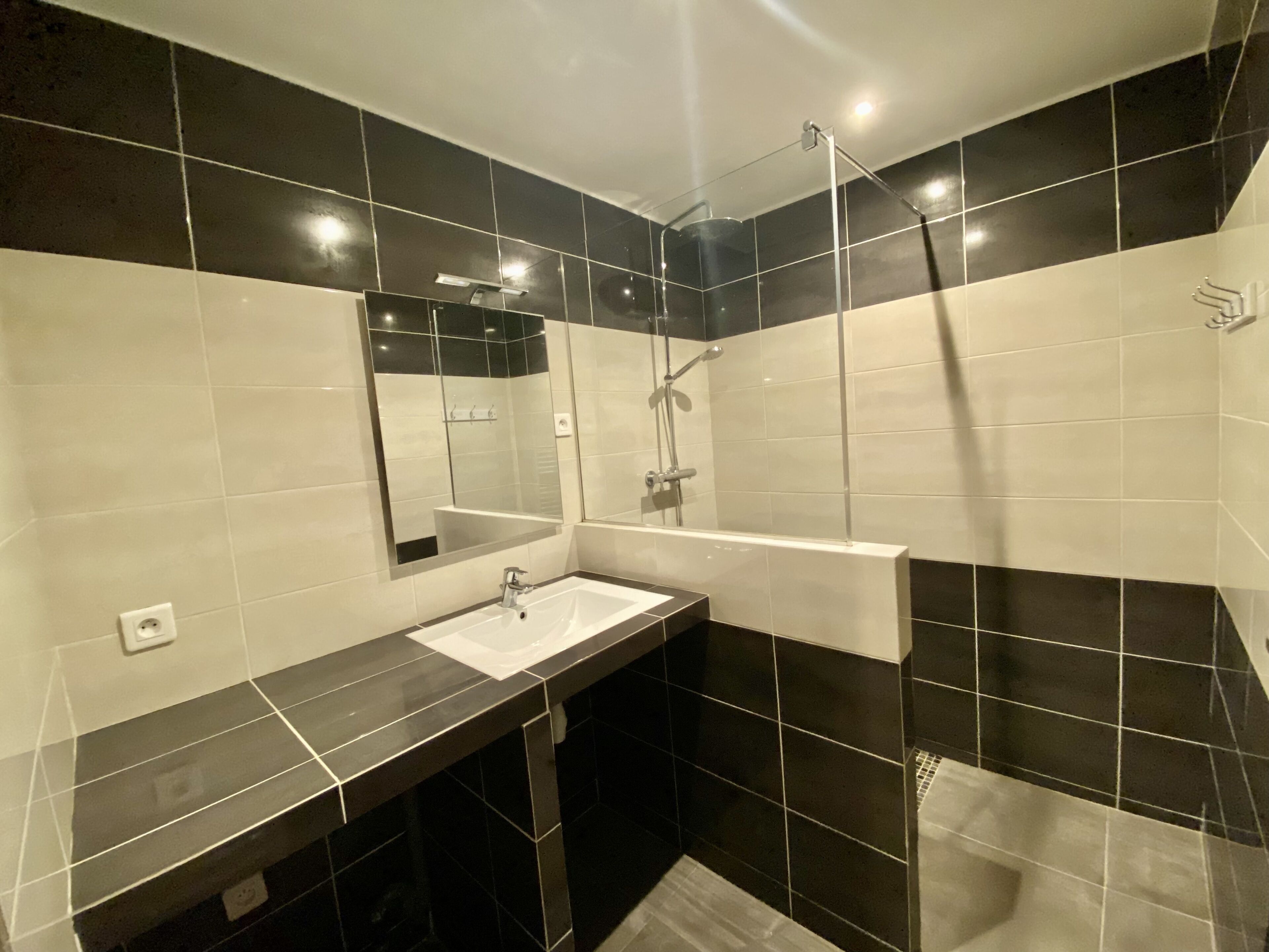Un baño moderno con un espejo grande, un lavabo y una zona de ducha.
