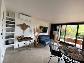 Una sala moderna con un sofá, una mesa de comedor y un ventanal con vistas a la vegetación.